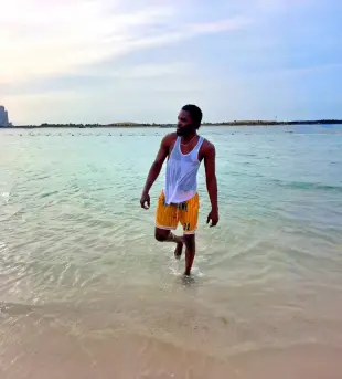 AI Video: A realistic cinematic scene of a man standing in shallow ocean water at the...