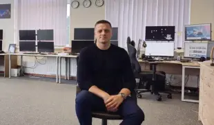 AI Video: A man sitting on a chair in a modern trading office full of multiple computer...