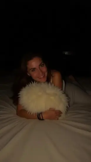 AI Video: She leans back, chest rising with a throaty laugh, then rolls onto her...