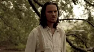 AI Video: Man standing in the rain. in a forested area with his head down. raises his...