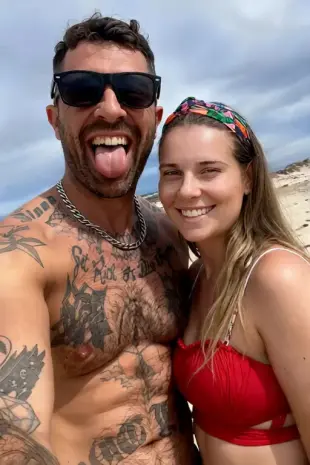 AI Video: The woman puts her left hand on the man's waist while smiling to the camera....